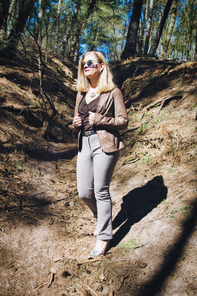 Frau im Wald mit Lederjacke und Sonnenbrille
